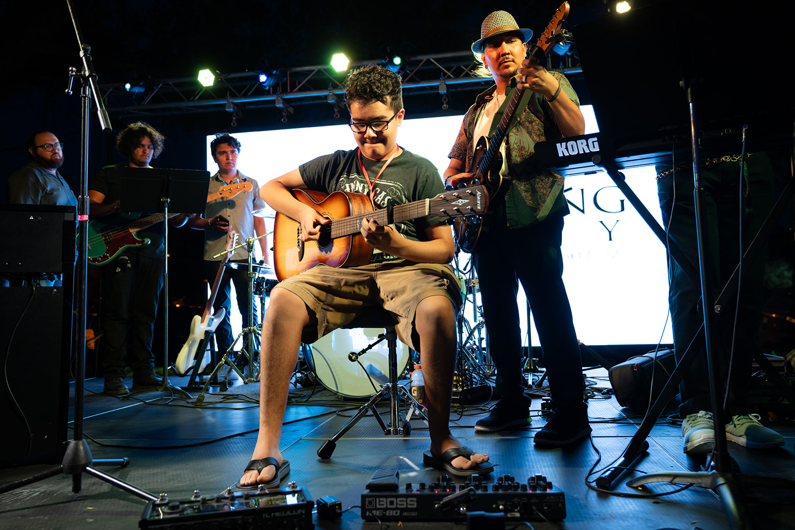 Acoustic guitarist and festival musicians performing after dark